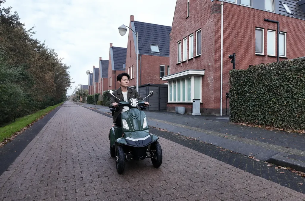 Man riding a Vista Quater-Pro 1000W electric scooter along a outdoor path.
